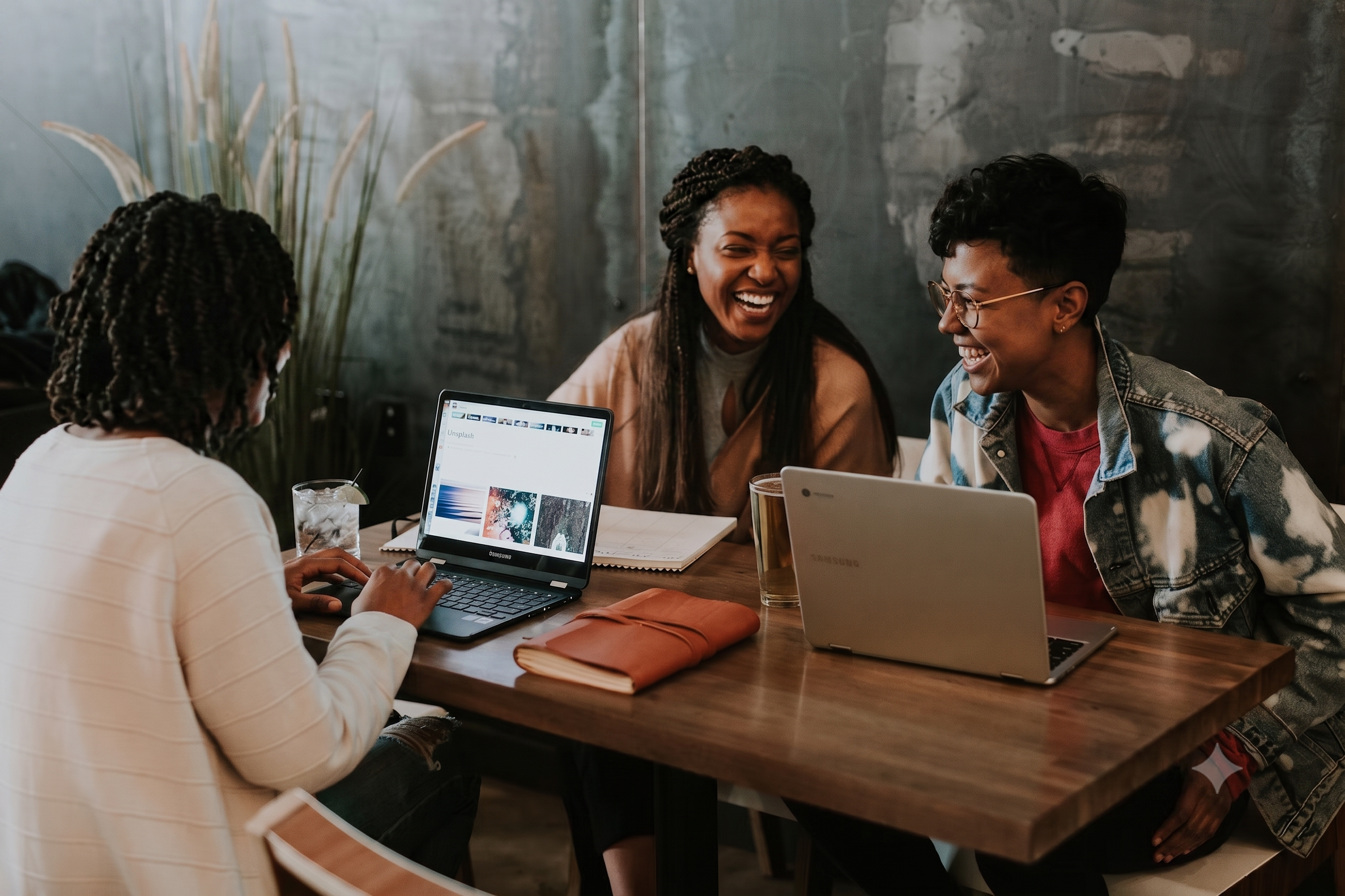 People laughing and collaborating around a laptop
